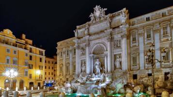 Una maestosa fontana con sculture elaborate e un grande edificio decorato sullo sfondo.