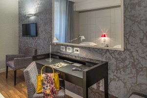 A modern hotel room with a desk, chair, and a large mirror.