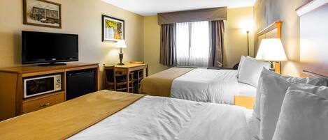 A hotel room with two beds, a TV, a desk, and a microwave.