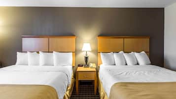 A hotel room with two beds, a nightstand with a lamp, and a phone.