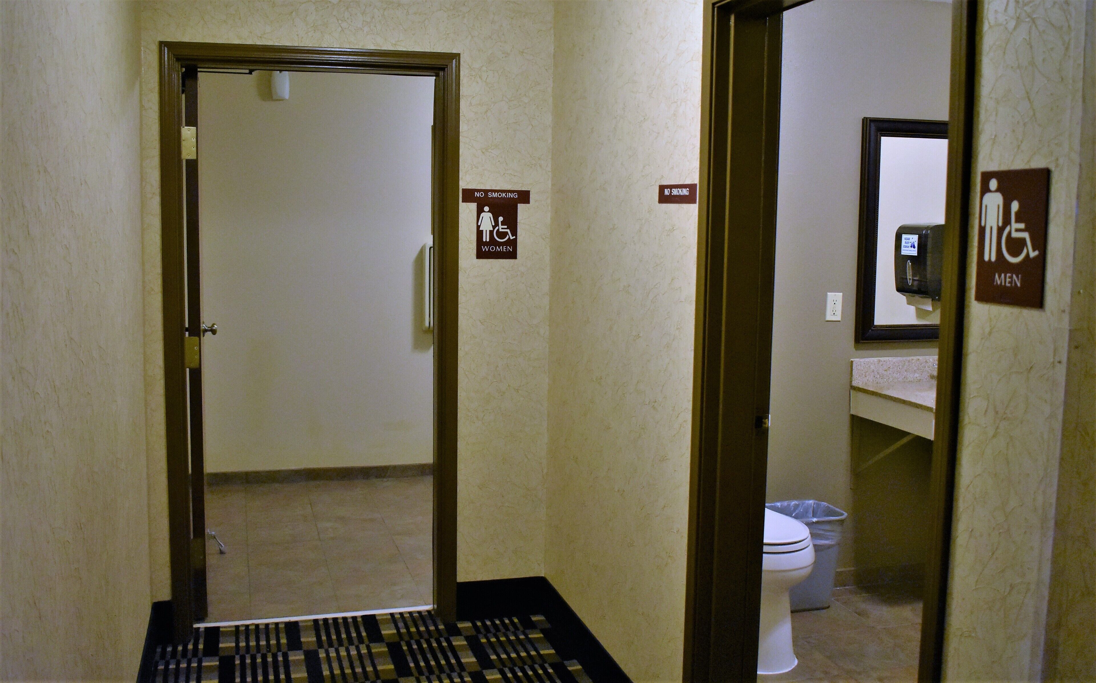 A hotel bathroom with a no smoking sign, a women's restroom sign, and a men's restroom sign.