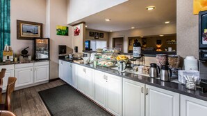 Zona de desayuno de hotel con un bufé, que incluye diversas opciones de comida y máquinas de café.
