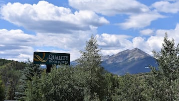 A sign for Quality Inn & Suites with a mountainous backdrop.