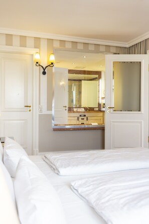 Habitación de hotel con cama, baño con espejo y lámpara de pared.