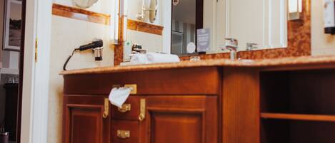 A bathroom with a wooden vanity, a large mirror, and a towel hanging on the door.
