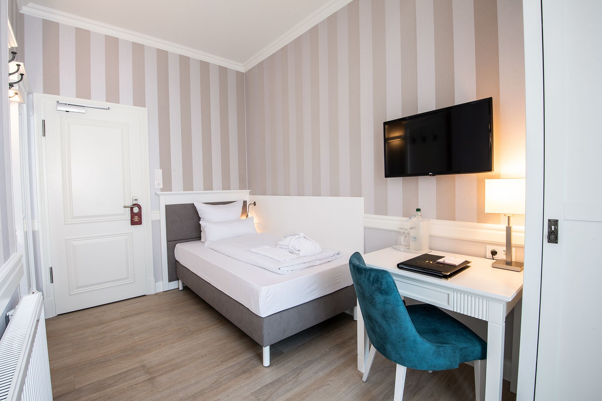 Een hotelkamer met een bed, bureau, stoel, televisie en radiator.