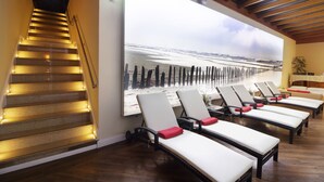 A hotel room with a beach view, a staircase with illuminated steps, and several sun loungers with red cushions. - Hotel IV Jahreszeiten Kühlungsborn  (Kuehlungsborn)