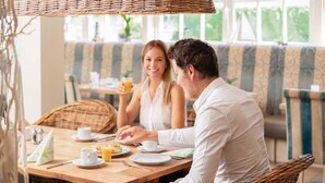 A dining area with wicker furniture, a wooden table, and a bench. - Hotel IV Jahreszeiten Kühlungsborn  (Kuehlungsborn)