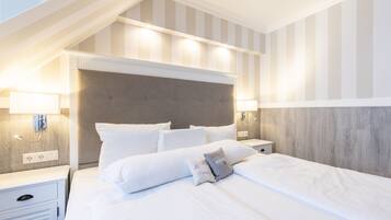 A hotel room with a large bed, two bedside tables, a headboard, and a striped wall.