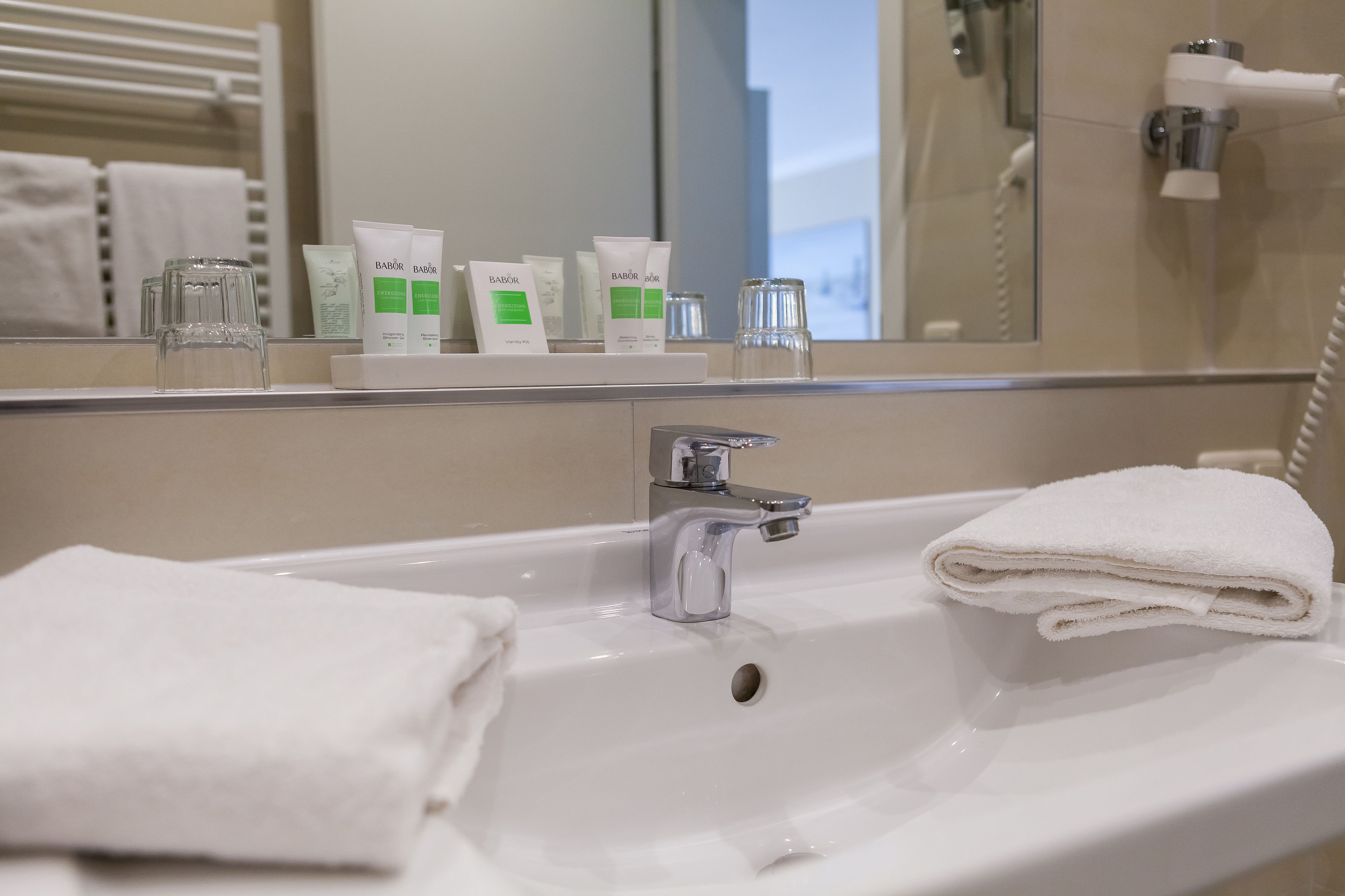 A hotel bathroom with a sink, a mirror, and toiletries.