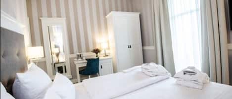 Una habitación de hotel con cama, escritorio, armario y televisor.