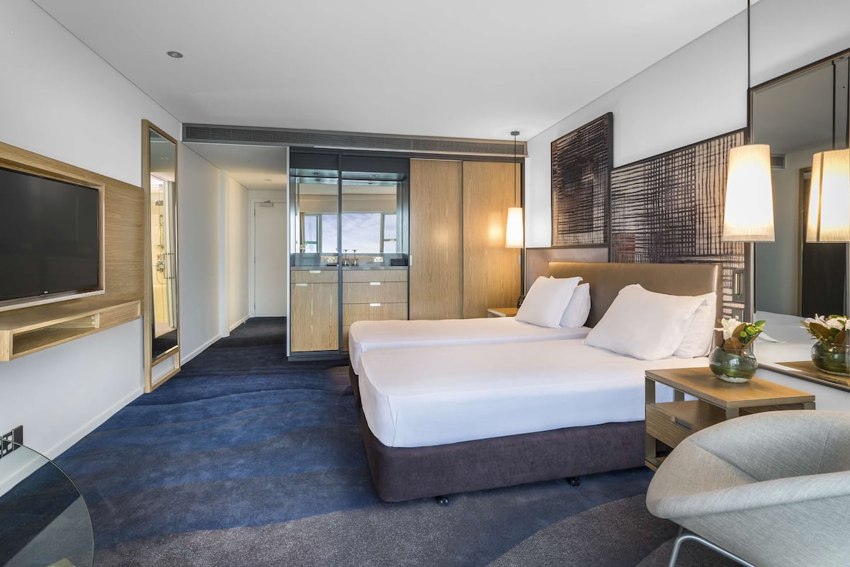 A hotel room with a large bed, a TV, a desk, and a bathroom visible through an open door.