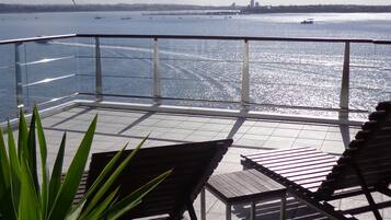 Une terrasse avec vue sur la mer, agrémentée d’une balustrade, de deux fauteuils et d’une plante en pot.