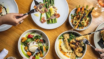 A group of people dining at a wooden table with various dishes, including seafood and vegetables.