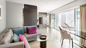 A modern living room with a sofa, a glass coffee table, and a view of the outdoors.