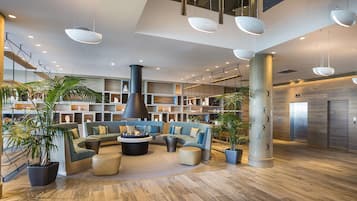 A spacious lobby with a central seating area, a large pillar, and a modern ceiling design.
