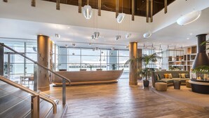 Un hall d’entrée spacieux avec un plancher en bois, un grand bateau en bois et un coin salon comprenant un canapé et un pouf.