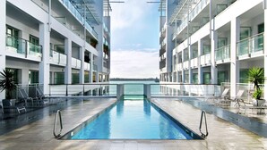 A modern hotel with a central swimming pool, balconies, and a view of the sea. - Hilton Auckland (Auckland)