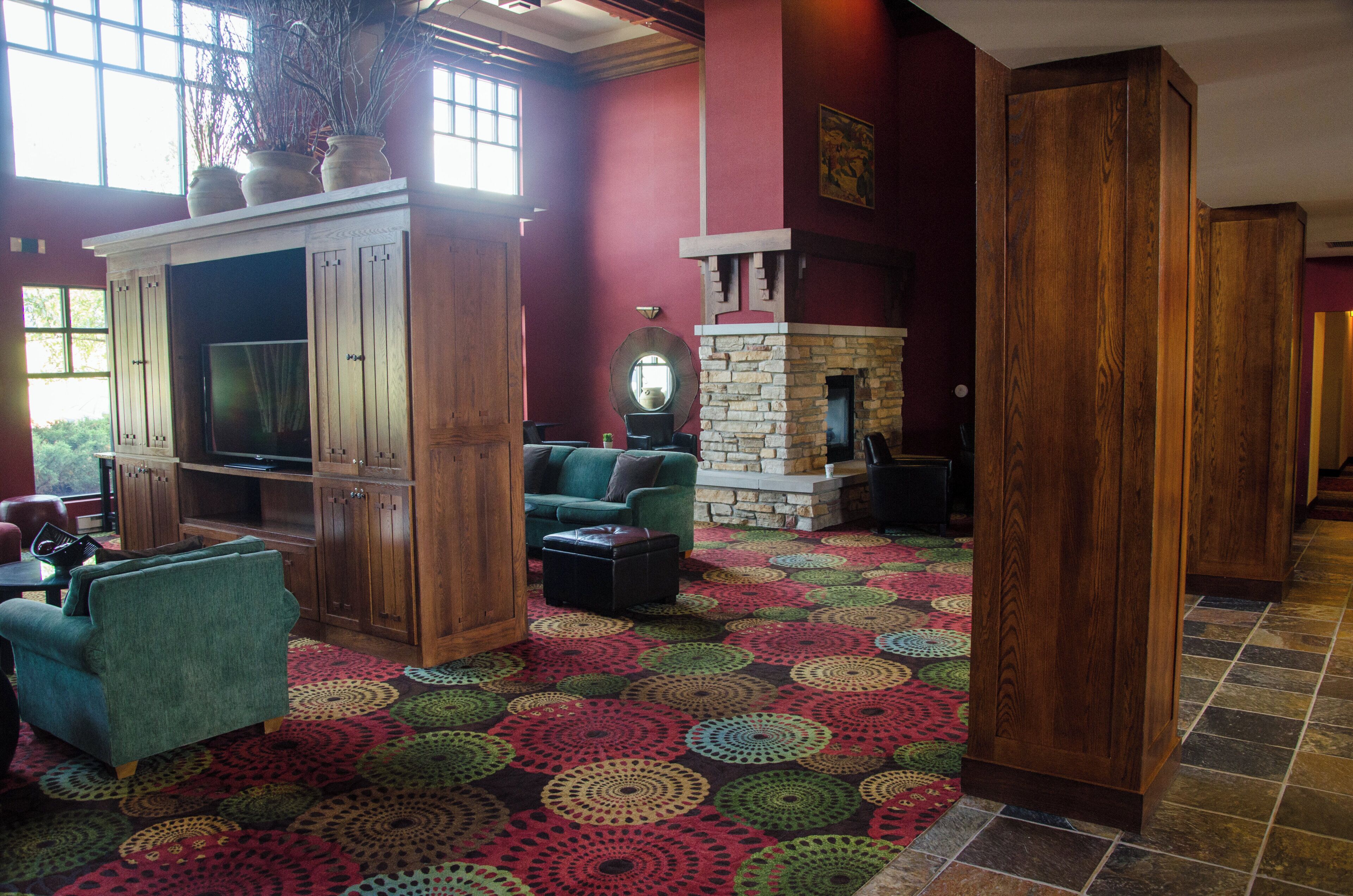 A spacious living area with a fireplace, a television, and a colorful patterned carpet.