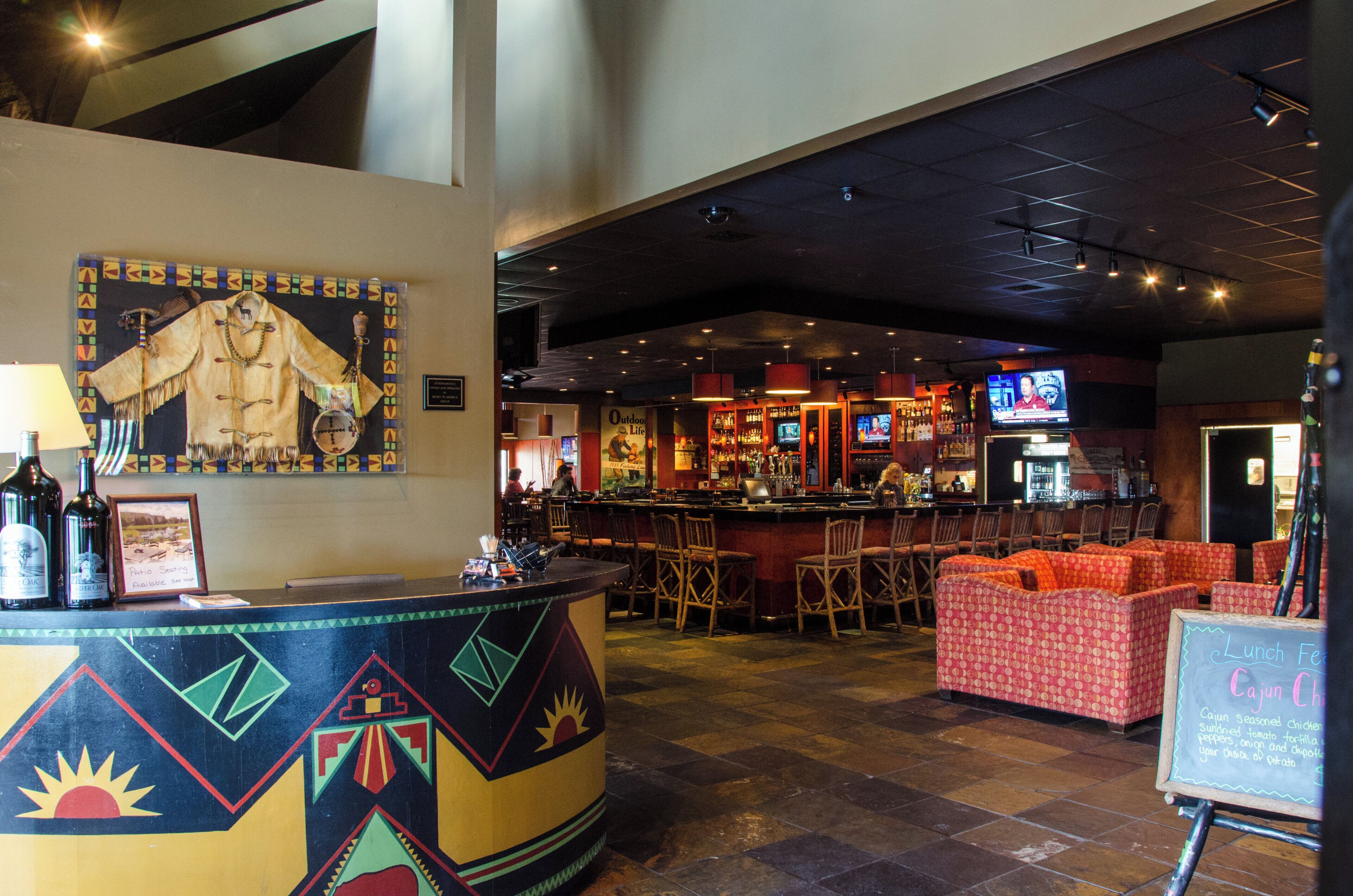 A bar area with a counter, bar stools, and a television screen.