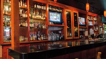 Een bar met drankflessen op de planken en een televisiescherm waarop een nieuwsuitzending draait.