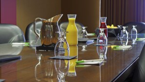 A conference table with various glassware and a pitcher of yellow liquid, likely juice, in a meeting room. - Holiday Inn Pewaukee - Milwaukee West by IHG (Pewaukee)