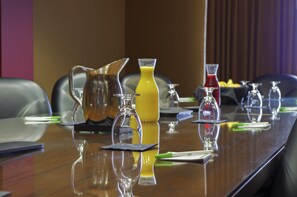 A conference table with various glassware and a pitcher of yellow liquid, likely juice, in a meeting room. - Holiday Inn Pewaukee - Milwaukee West by IHG (Pewaukee)