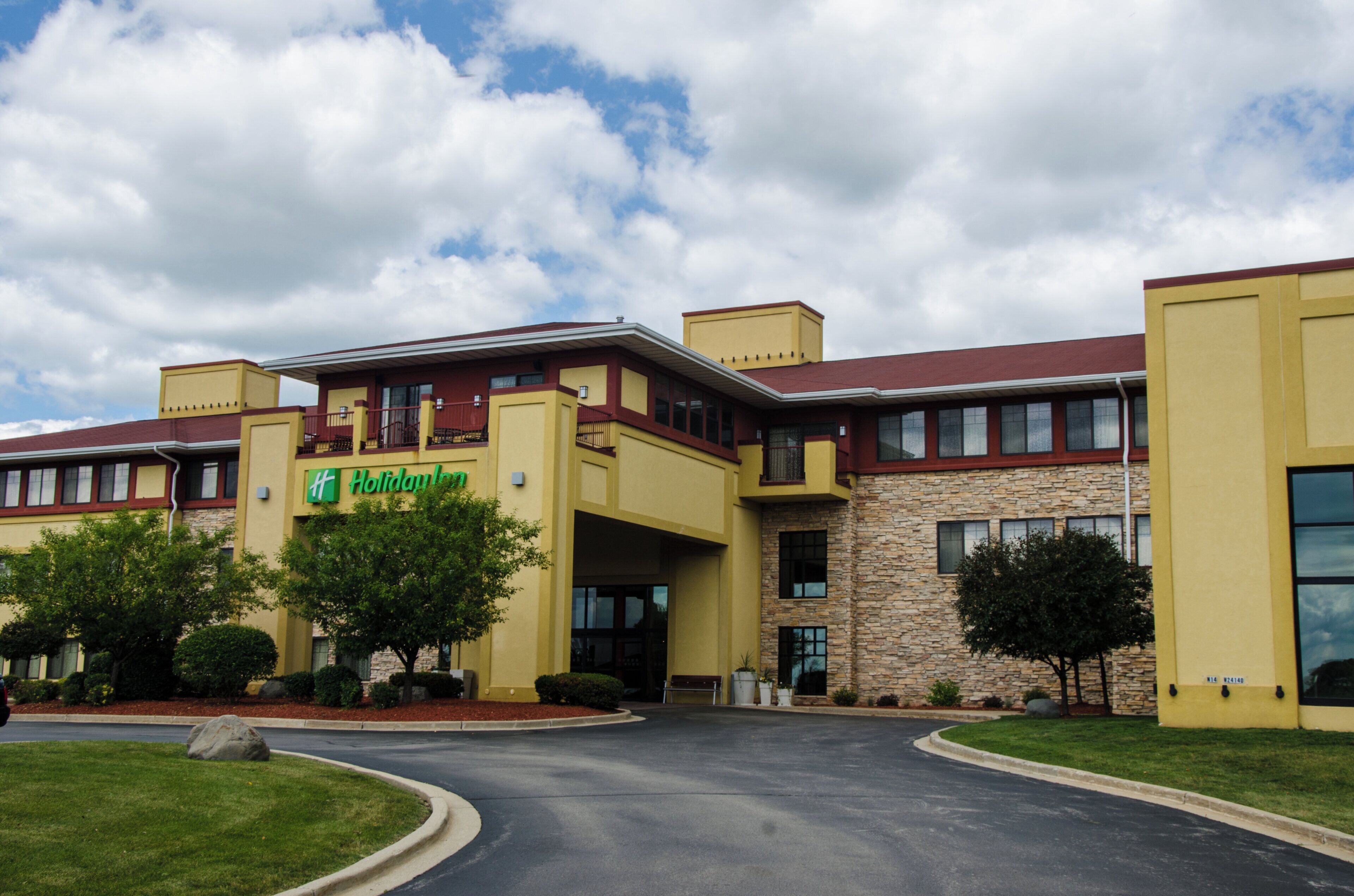 A Holiday Inn Express hotel with a yellow facade, stone accents, and a red roof.