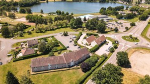 An aerial view of a residential area with a large building, roads, and a lake.