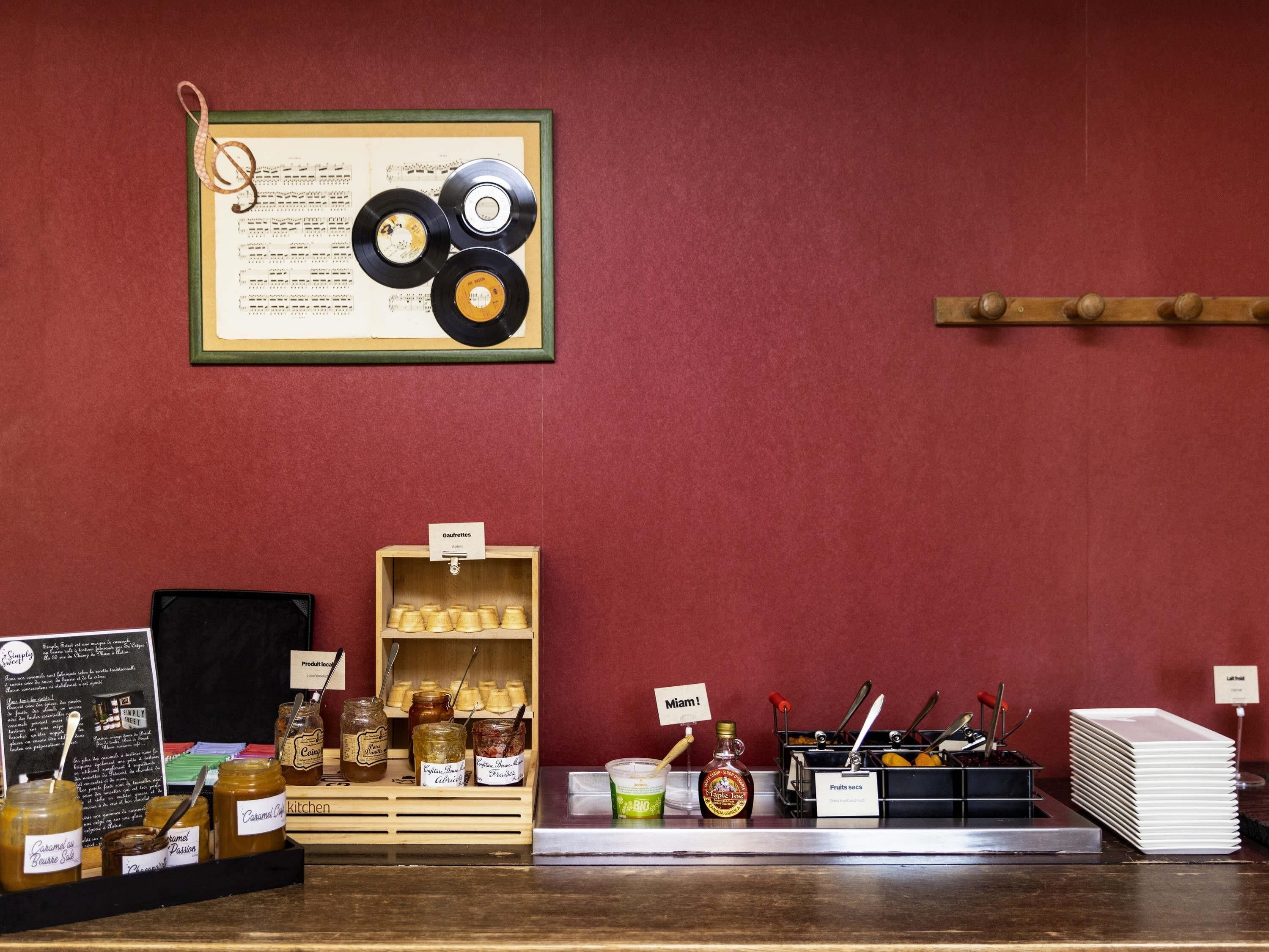 A counter with jars of honey, a sign reading 'Gaufrettes,' and a framed record collection on the wall.