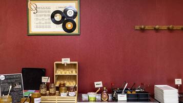 A counter with jars of honey, a sign reading 'Gaufrettes,' and a framed record collection on the wall.