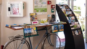 Zona de recepción con una bicicleta, un mapa y una exposición de postales.