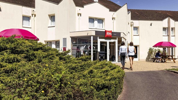 A hotel with a modern facade, a red ibis logo, and a welcoming entrance.