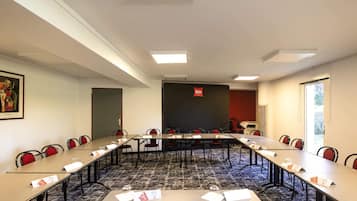 A conference room with a long table, chairs, nameplates, and a blackboard with 'ibis' written on it.
