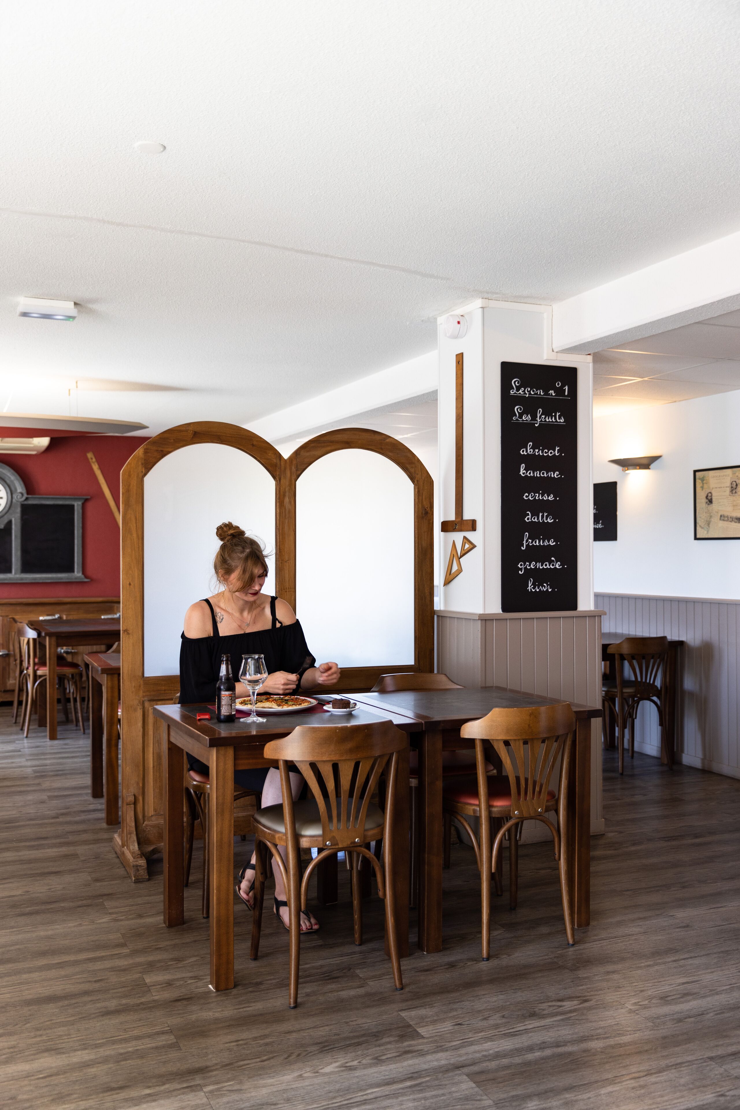 Un interno ristorante con arredi in legno, un menu scritto su lavagna e una parete decorata di rosso.
