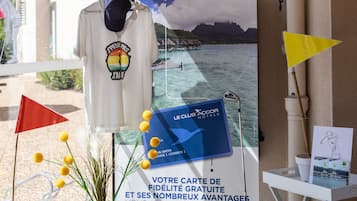 Entrada de hotel con un cartel para Le Club Accor Hotels, un letrero de bienvenida y una exhibición de servicios que incluye un mapa, un sombrero y una pequeña estatua.