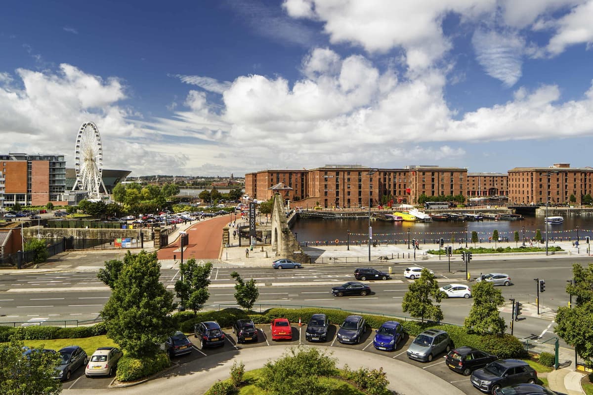 A cityscape with a river, a Ferris wheel, and a modern building with a brick facade.