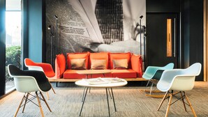 A modern lounge area with a red sofa, two white chairs, and a round table.