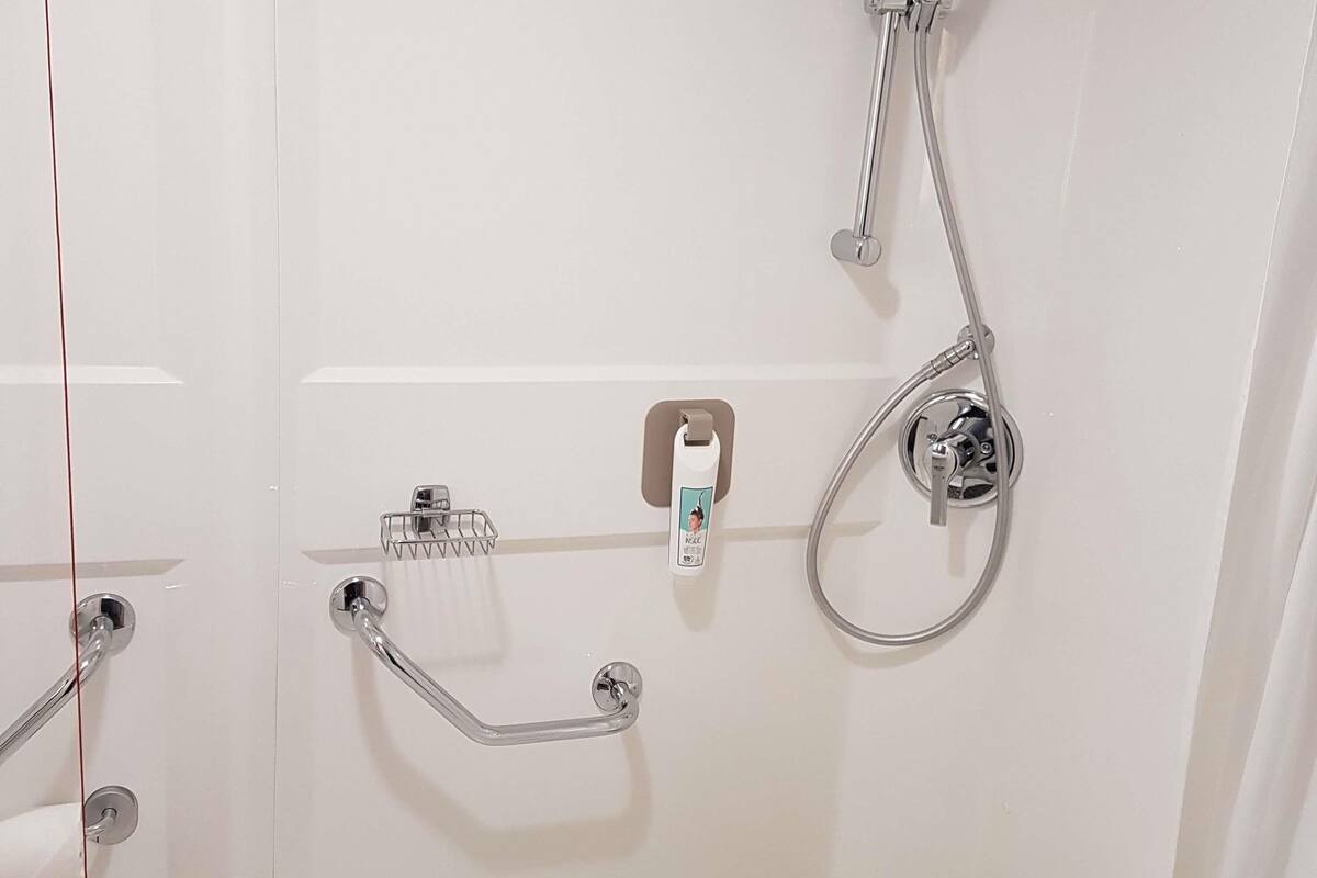 Une salle de bain équipée d’une douche, de toilettes et d’une barre d’appui.