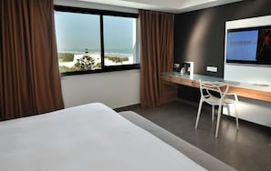 Een moderne hotelkamer met een groot bed, een bureau en uitzicht op de oceaan.