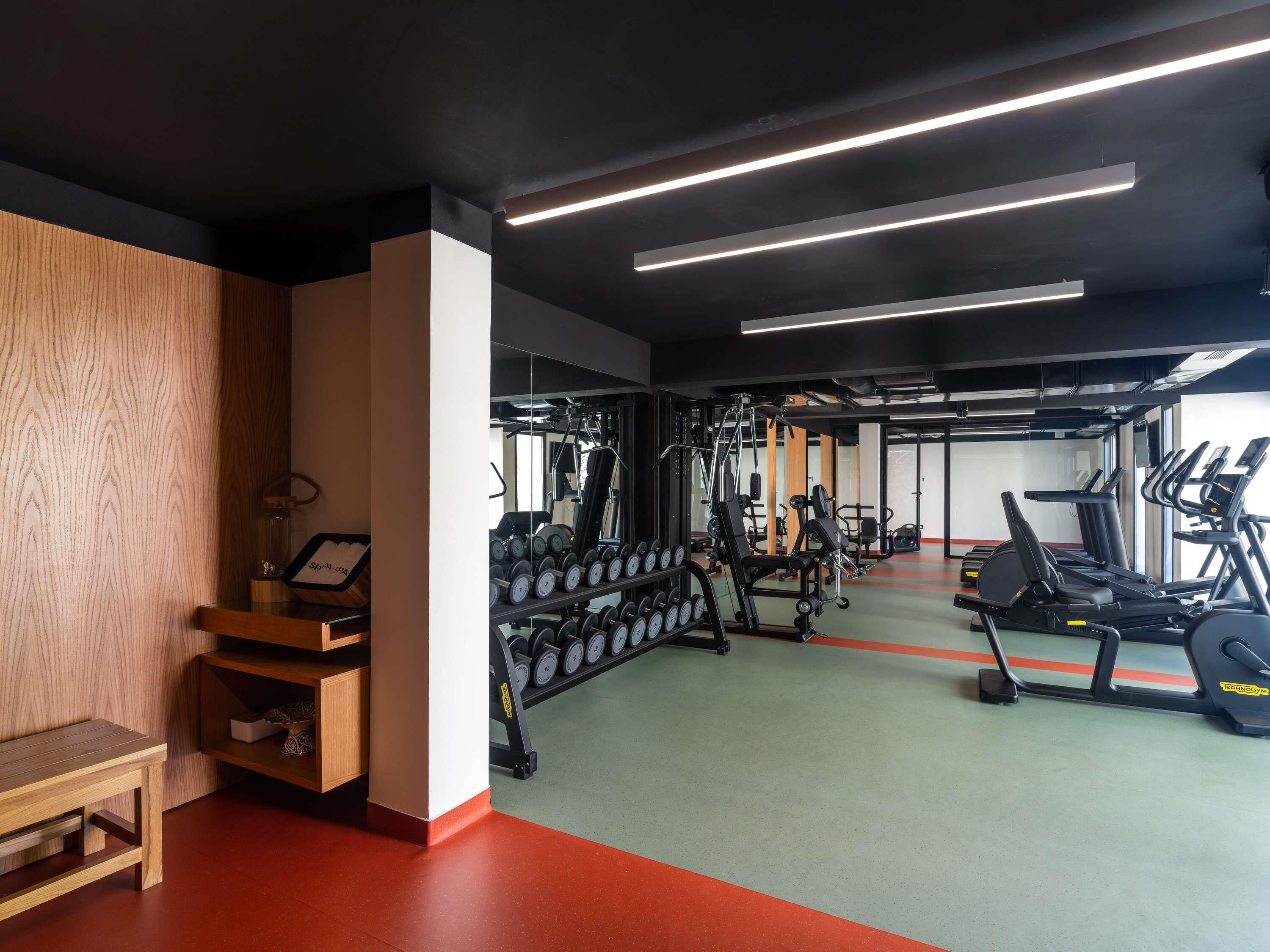 Un gimnasio con máquinas de pesas, cintas de correr y mancuernas.