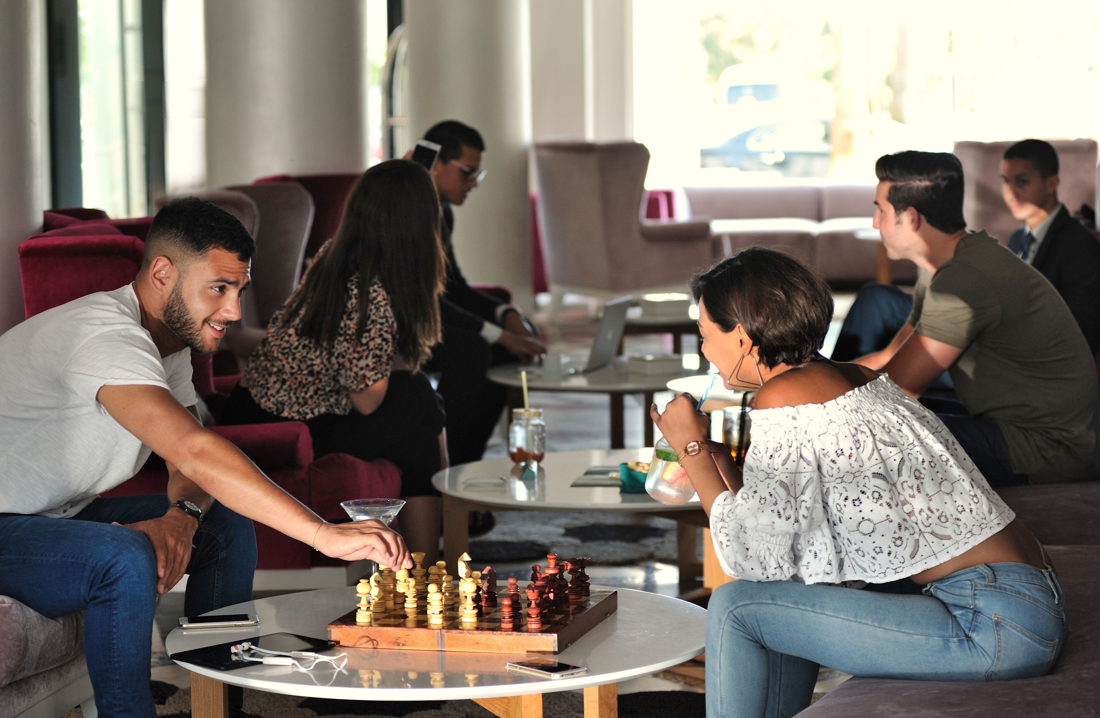 Un grupo de personas jugando ajedrez en un ambiente interior moderno, con asientos cómodos y un ambiente relajado.