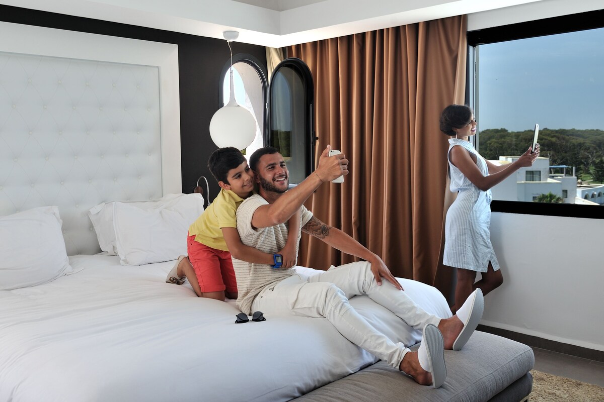 Habitación de hotel moderna con una cama grande, vistas de la ciudad y un balcón.