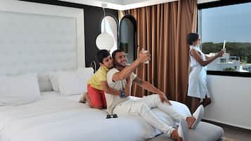 A modern hotel room with a large bed, a view of the city, and a balcony.
