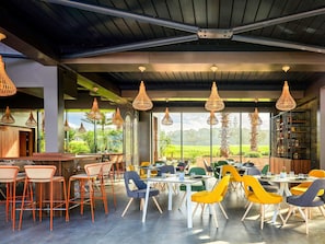 Un comedor moderno con techos altos, vigas a la vista y grandes ventanales que ofrecen vistas al verdor.