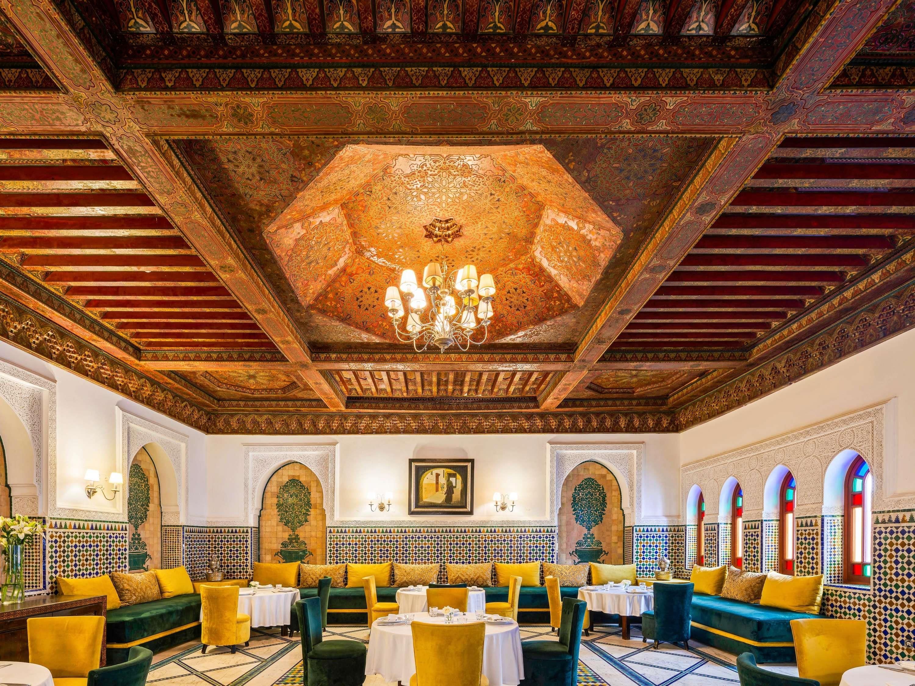 Un interior lujoso con techo ornamentado, zonas de estar y decoración tradicional.