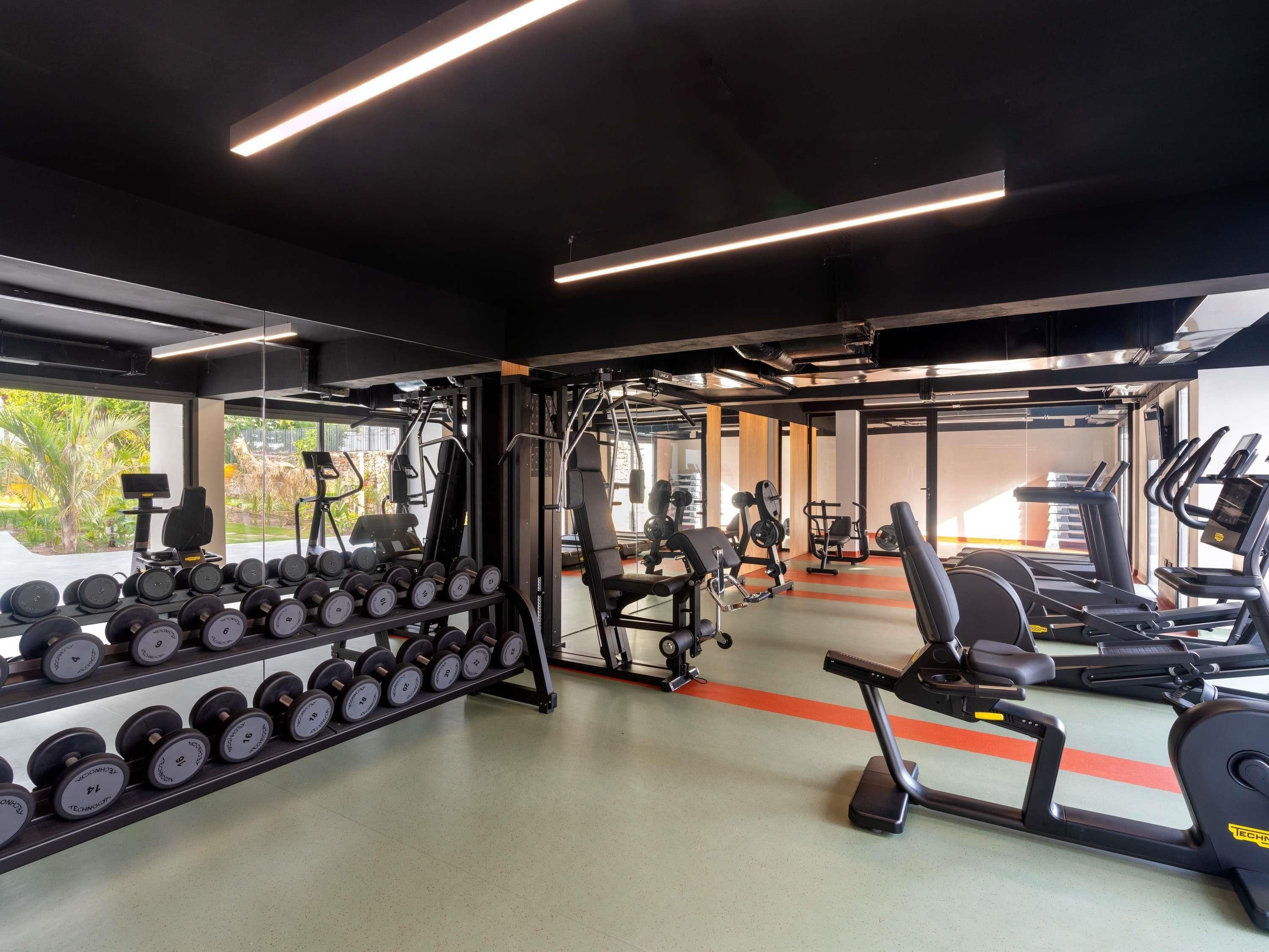 Un gimnasio con equipo de ejercicio, un estante de pesas y una cinta de correr.