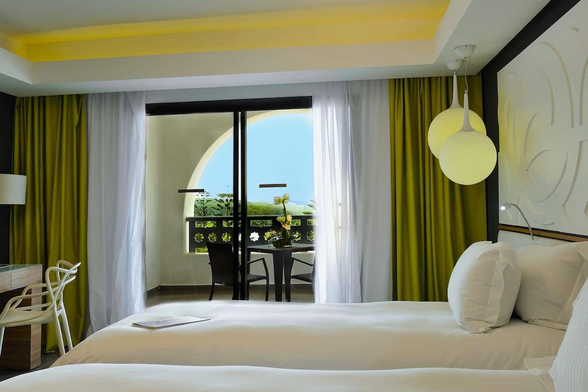Een hotelkamer met een bed, een bureau, een stoel en een balkon met uitzicht.