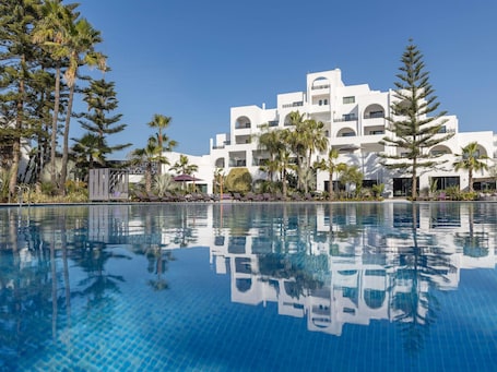 Una piscina al aire libre, sombrillas, sillones reclinables de piscina