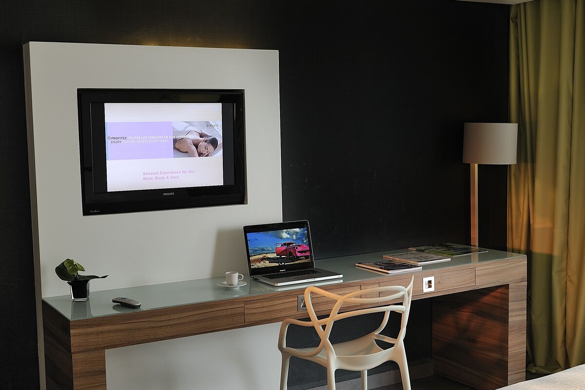 Una habitación de hotel con escritorio, computadora portátil, silla y dos camas.